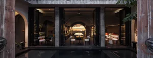 Industrial-themed restaurant lounge with concrete walls, glass dining area, and modern decor.