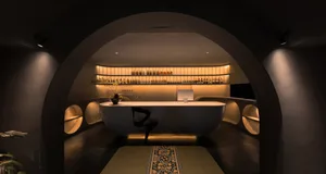 A minimalist spa interior with a concrete bathtub and shelving.