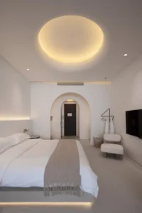 Modern minimalist bedroom featuring a king-sized bed with neutral bedding and a circular light fixture above