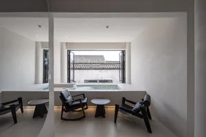 A modern residential interior with a minimalist design featuring concrete elements, including a small pool and seating area w