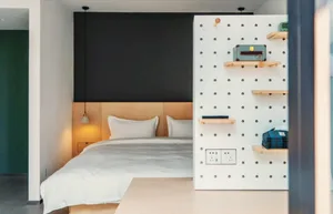 Modern minimalist bedroom with a bed featuring white bedding and a white wooden headboard, illuminated with warm lighting fro