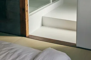 Minimalist room with white walls, wooden floor, and white tile balcony, featuring neutral tones and clean lines.