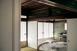 Modern minimalist Japanese bedroom featuring white bedding, paper sliding doors, and wood accents.