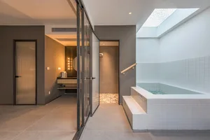 A modern bathroom with a white tile tub and grey walls.
