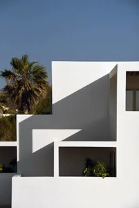 A modern building facade with white walls and green plants.