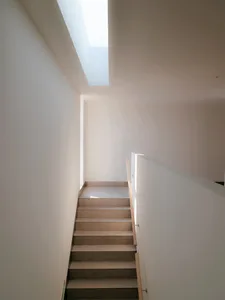 Modern concrete staircase with white walls and a skylight.