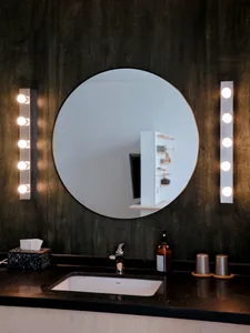 A modern industrial bathroom featuring dark wood paneling and metal lighting fixtures.