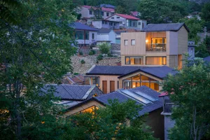 View of a modern residential house with multi-story design and illuminated windows.