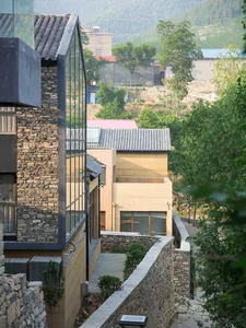 Modern residential house with wooden exterior, glass windows, stone accents, and metal roof.