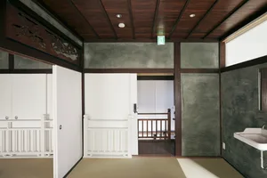 A traditional Japanese interior with wooden walls and doors, tatami mats, and a sink.