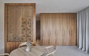 A minimalist interior space featuring wooden cabinets and a round wooden table with a vase of flowers.