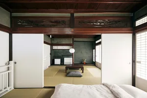 A minimalist living room with tatami mats, wooden furniture, and plaster walls.