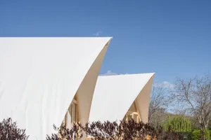 Modern building with a white fabric exterior under a clear blue sky.