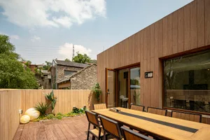 Modern exterior with wooden fence, table, and chairs in a landscaped area.