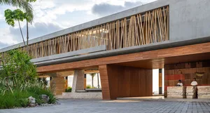 Modern hotel entrance featuring large concrete structure with bamboo and wooden accents.