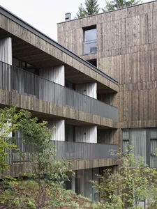 A modern residential building with a wooden exterior and balconies.