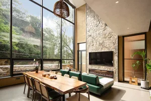 A modern living room featuring natural stone walls and a wooden table with chairs.