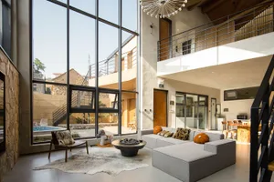 A modern living space with concrete walls and a fireplace, featuring a comfortable grey sofa and a cowhide rug.