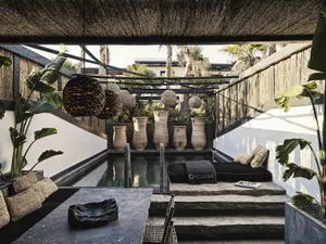 Modern pool area with concrete surfaces, ornamental pots, and tropical plants.