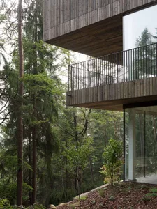 A modern treehouse designed for forest-oriented living, featuring wooden exteriors and glass walls.