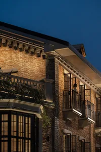 A cozy brick building at night with a person standing on a balcony
