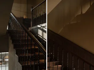 Interior shot of a dark staircase with wooden steps and a metal railing, featuring geometric patterns and modern design eleme