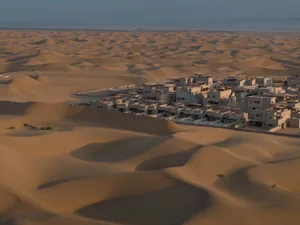 Concrete buildings amidst sandy desert dunes