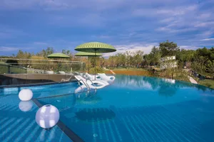 A glass swimming pool with umbrellas and loungers