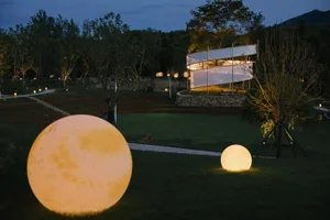 A night scene featuring illuminated light spheres in a well-lit park setting with trees and stairs.