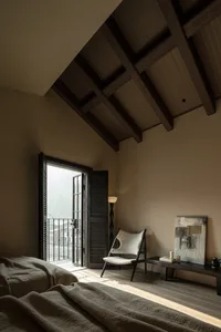 Minimalist bedroom featuring wooden furniture and structures under a high, wooden beam ceiling.
