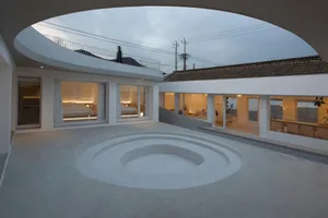 Minimalist concrete residential space with circular terraced courtyard and indoor/outdoor living.