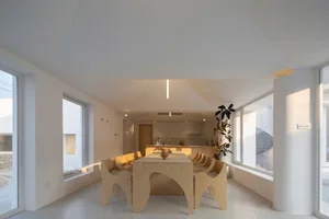 Modern minimalist dining room interior featuring wooden table, chairs, and glass windows, with a potted plant adding life to