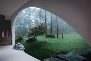 A minimalist landscape featuring grass, rocks, and trees under foggy weather conditions.