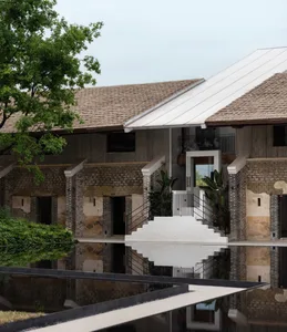 A modern building with concrete exterior and roof reflection in a pool.