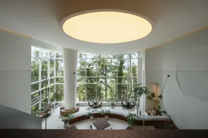 Modern cafe interior featuring large glass windows, concrete floor, and circular light fixture.
