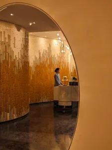 A modern hotel lobby featuring marble tiles, wooden panels, and ambient lighting.