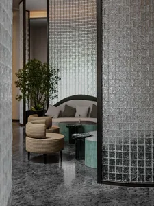 A modern lobby featuring metallic tiles and a circular seating area with a plant.