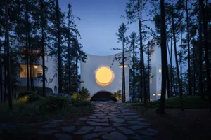 A modern, minimalist residential interior with a central circular light feature, illuminated at night.
