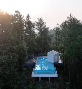A modern outdoor spa enclosed in glass, surrounded by lush greenery.