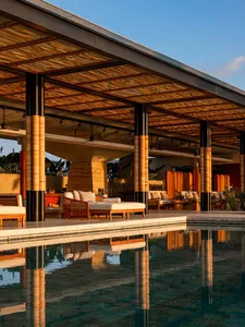 Modern residential space featuring a poolside area, wooden pergola, and glass walls.