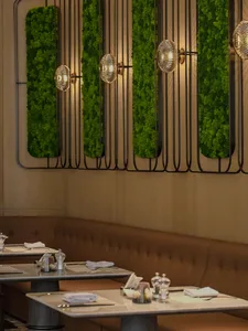 Modern restaurant interior with green living walls and metallic fixtures.