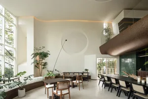 A modern restaurant interior with wooden furniture, white walls, and large windows.