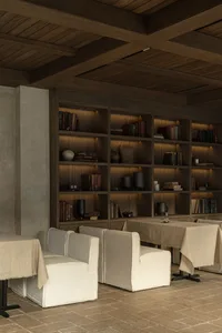 Modern restaurant library with wooden shelves and concrete wall