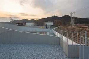 Modern rooftop with concrete deck, white railings, and views of mountains and hills.
