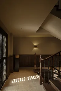 A modern staircase with wooden railings and illuminated by wall-mounted lights against a warm, neutral background.