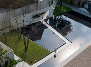 Modern urban garden with concrete pathway, water feature, and greenery.