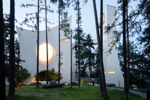 現代主義住宅建築，白色灰泥外牆，在黃昏時分被圓形燈光照亮。