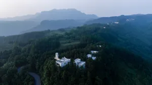 Aerial view of a luxurious mountain resort nestled in a forested area with modern architectural features and scenic mountain 