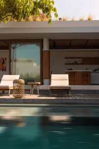 Poolside lounge area with white cushions and wooden furniture.