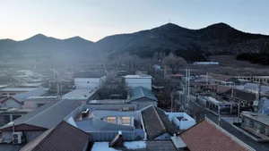 Aerial view of rooftops and mountains in an urban setting.